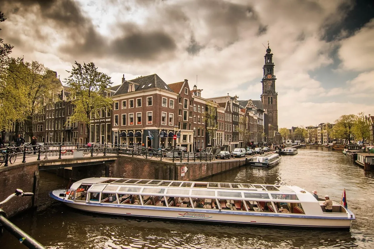 Un barco de canales con techo de cristal bajo la torre de la Westerkerk