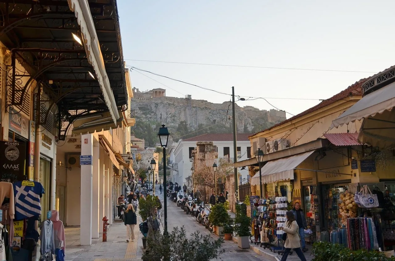 Una calle comercial de Plaka con la roca de la Acrópolis sobre los tejados