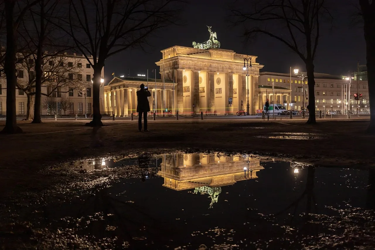La Puerta de Brandeburgo iluminada de noche, reflejada en un charco