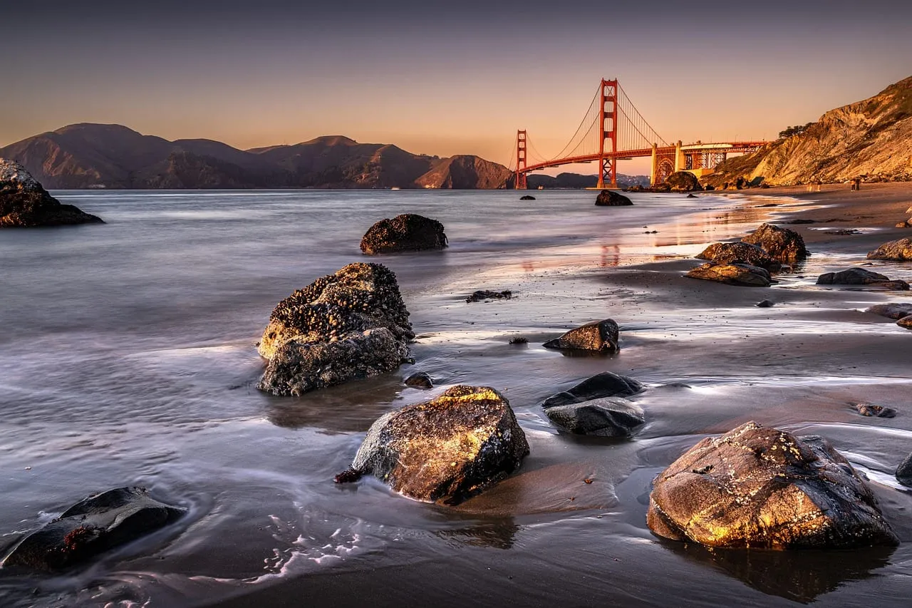 El puente visto desde una playa rocosa al atardecer