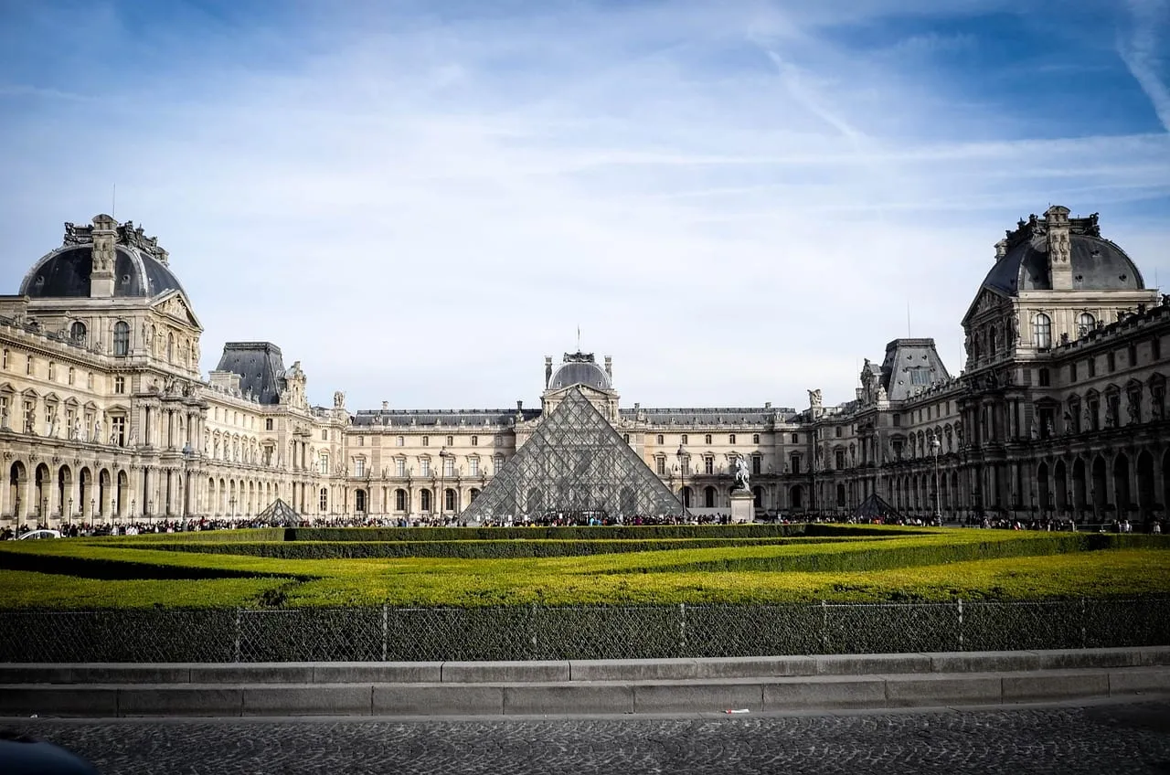 Las largas alas del Louvre en torno a la pirámide, vistas desde el otro lado de un césped