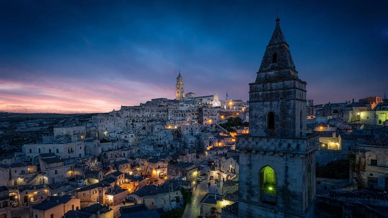 Los Sassi iluminados al anochecer bajo el campanario de una iglesia