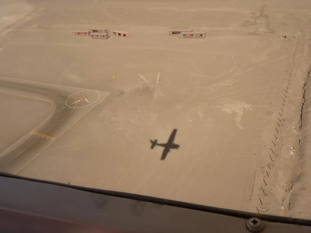 La sombra de una avioneta sobre la pista de aterrizaje