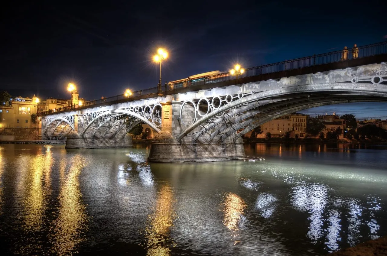 El puente de Isabel II hacia Triana, iluminado de noche sobre el Guadalquivir