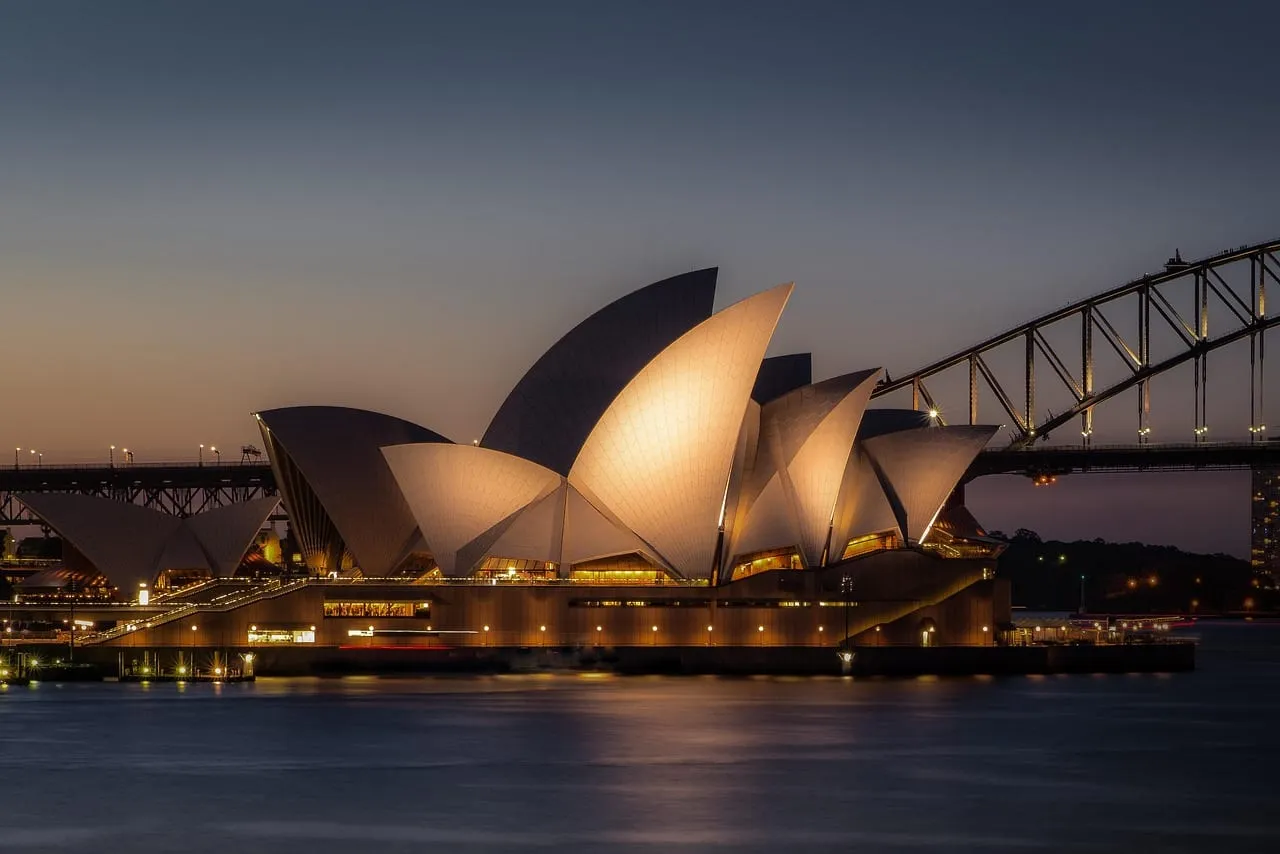 La Ópera iluminada al anochecer, con el Harbour Bridge detrás