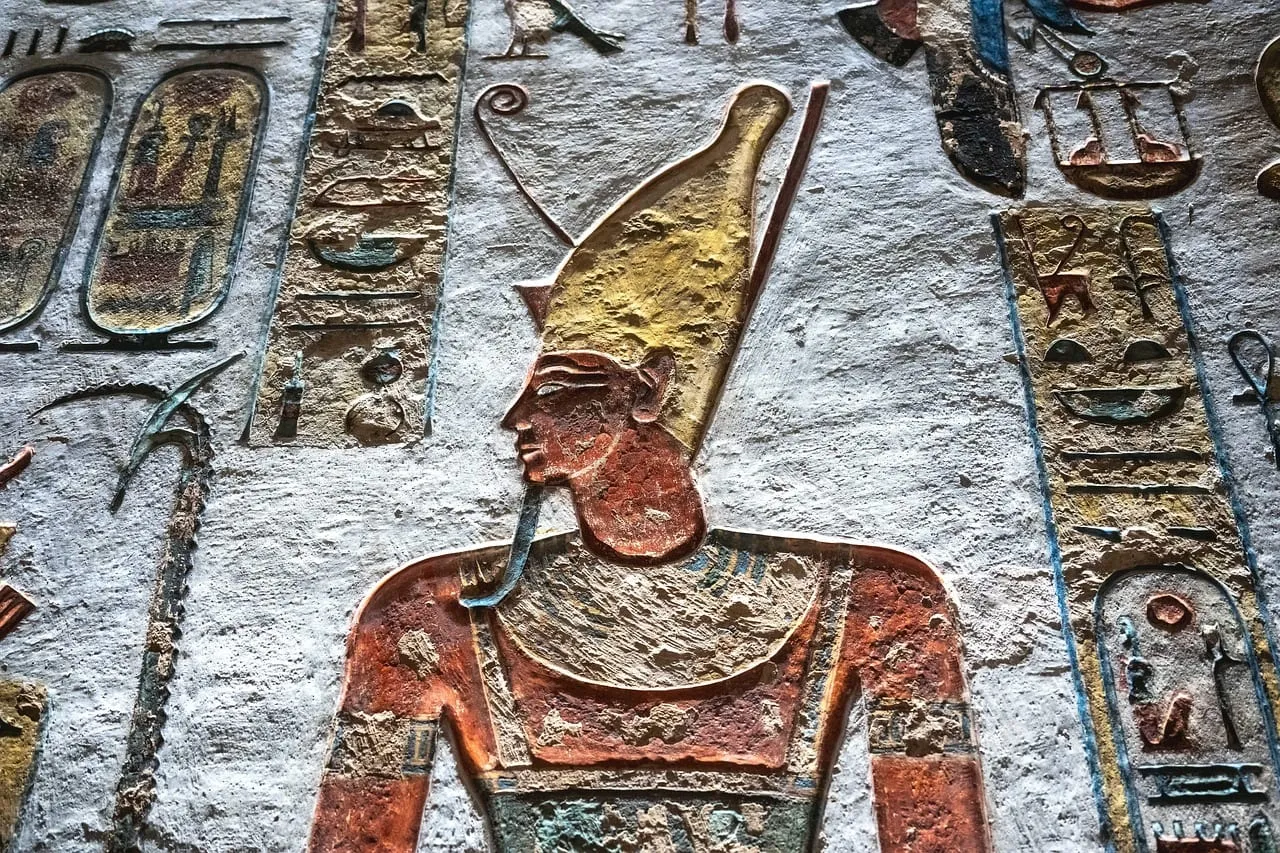 Un relieve pintado de un rey con una alta corona en la pared de una tumba